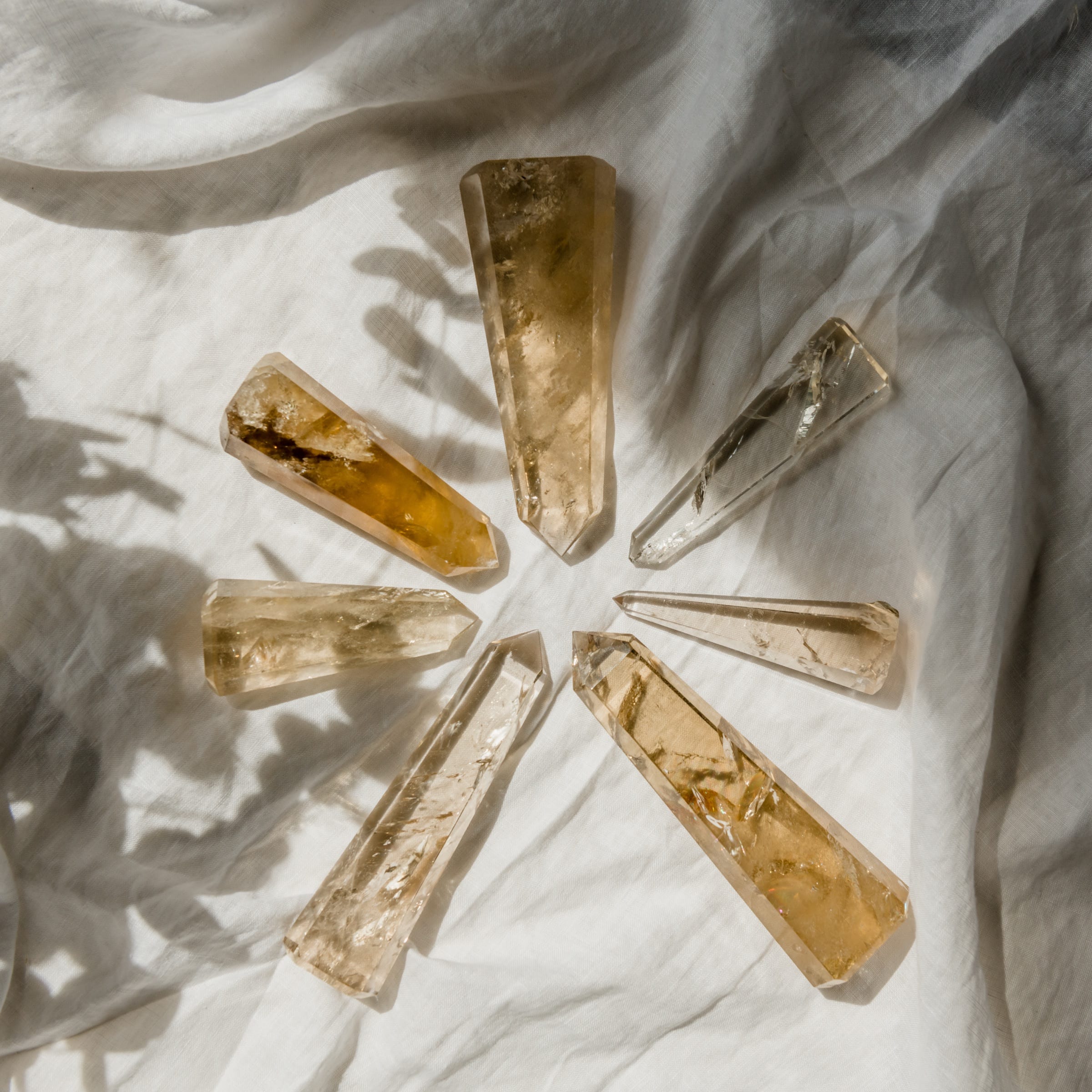 Polished quartz points laid in a fan on crumpled linen, photographed for a client.