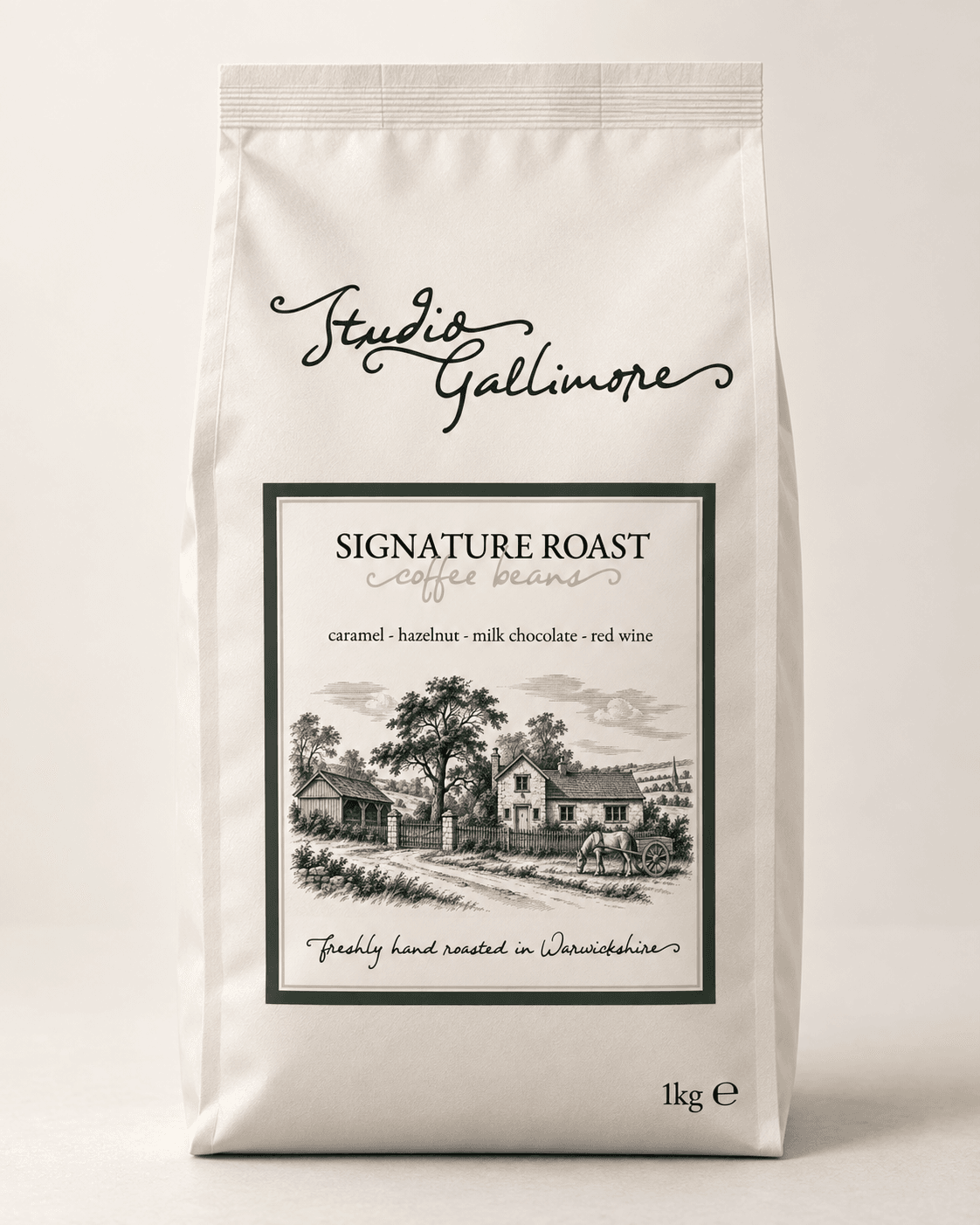 Studio Gallimore Signature Roast coffee beans, 1kg bag, cream with a deep green label and an engraved cottage scene.